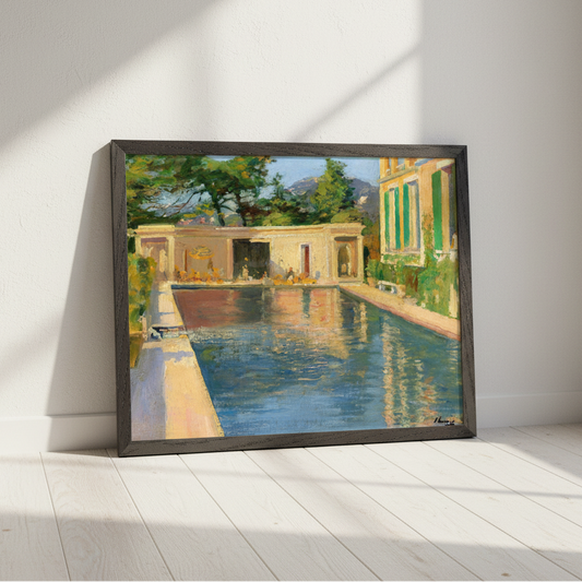 A framed painting of a Mediterranean-style poolside scene leaning against a white wall on a light wood floor, with strong diagonal sunlight casting shadows across the room.