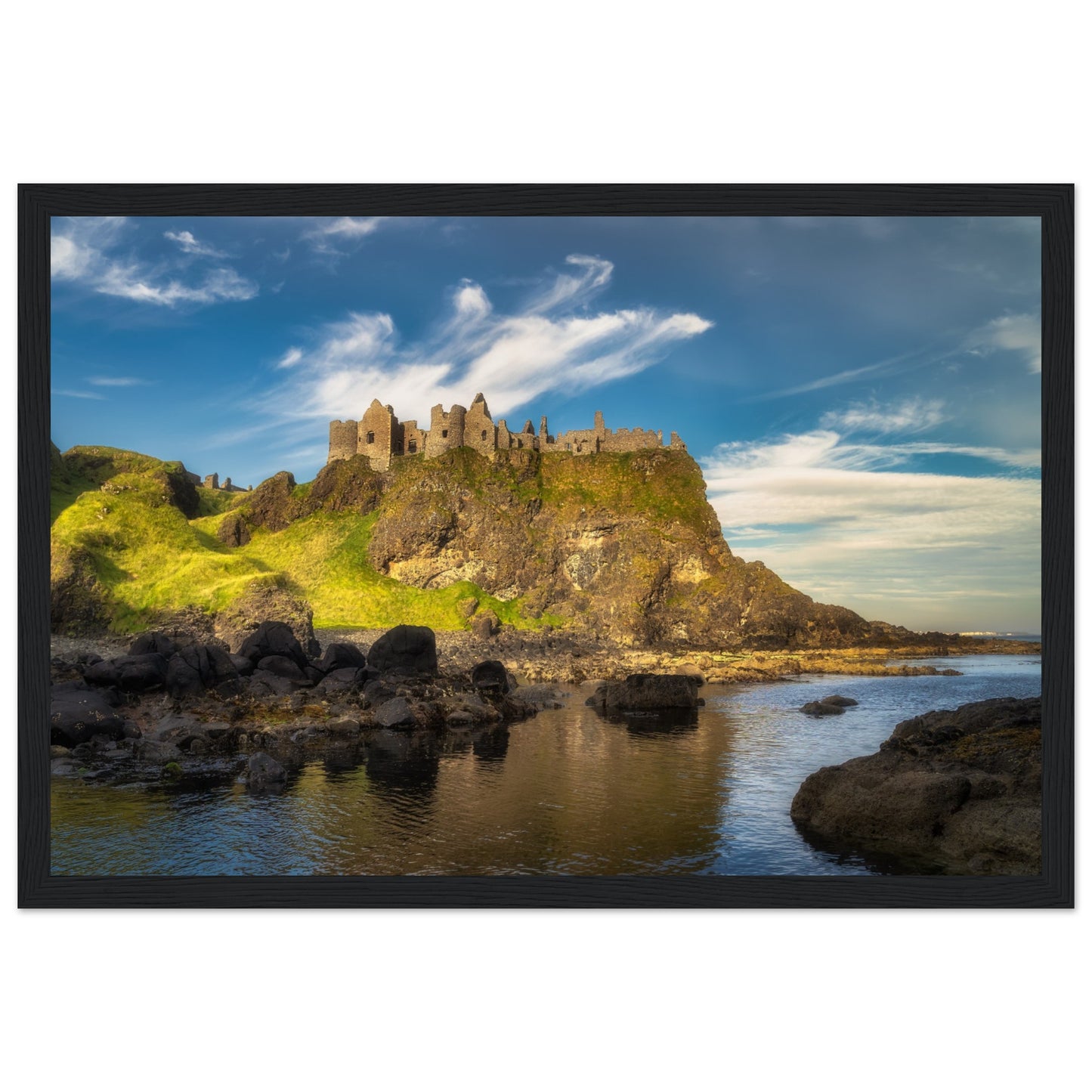 Framed wall art print of Dunluce Castle on the rugged cliffs of Northern Ireland. The medieval architecture and dramatic coastal scenery create a timeless, captivating image. Perfect for adding historical charm and natural beauty to any home decor setting.