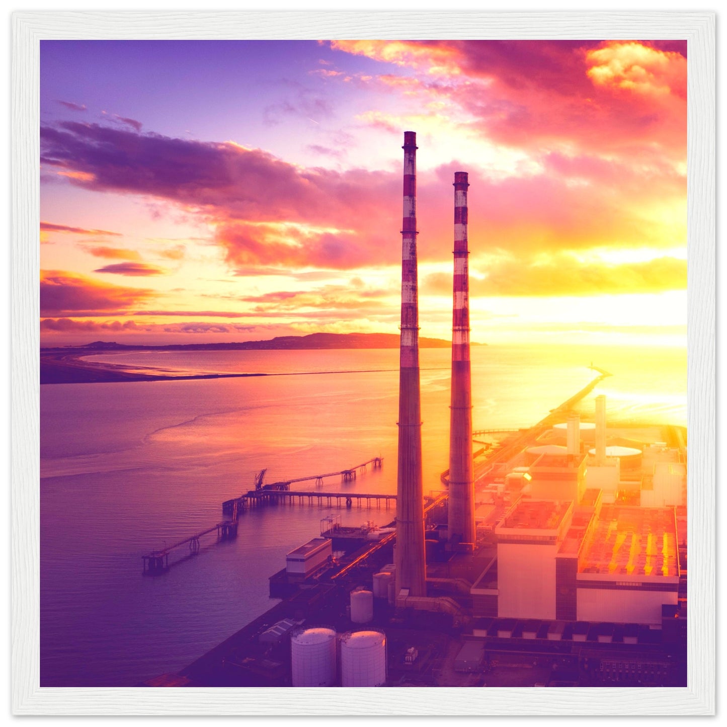 A framed print of Dublin's industrial landscape, featuring the iconic Poolbeg Towers and Lighthouse at sunrise. This aerial view captures the blend of industrial structures with a serene, sunlit horizon, showcasing the harmony between technology and nature. Perfect for admirers of drone photography, industrial architecture, and Ireland's coastal beauty.