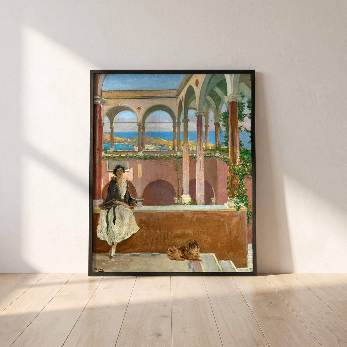 A Villa on the Riviera framed print in a black frame leaning against a white plaster wall on oak floorboards in morning light
