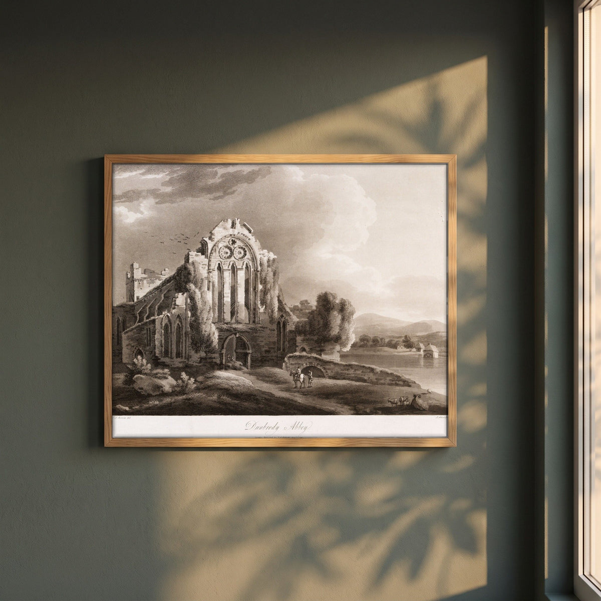 Dunbrody Abbey by Thomas Sautelle Roberts Art Print framed print in a natural oak frame on a dark green wall beside a window, dappled plant shadow