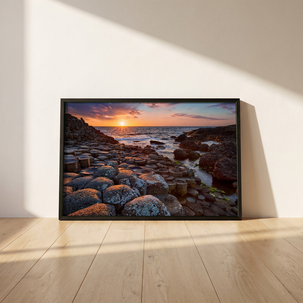 Giant's Causeway framed print in a black frame leaning against a white plaster wall on oak floorboards in morning light