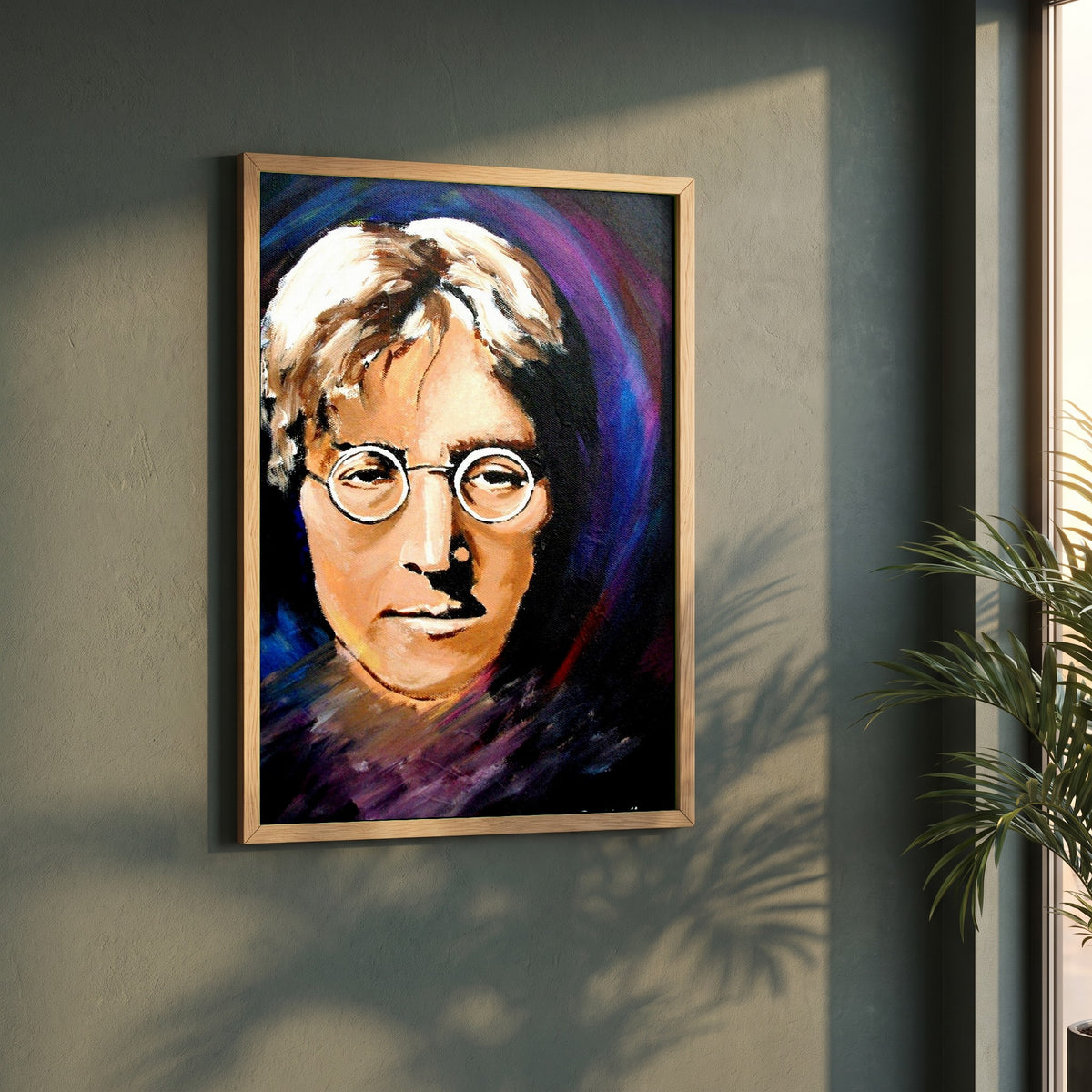 John Lennon Portrait framed print in a natural oak frame on a dark green wall beside a window, dappled plant shadow
