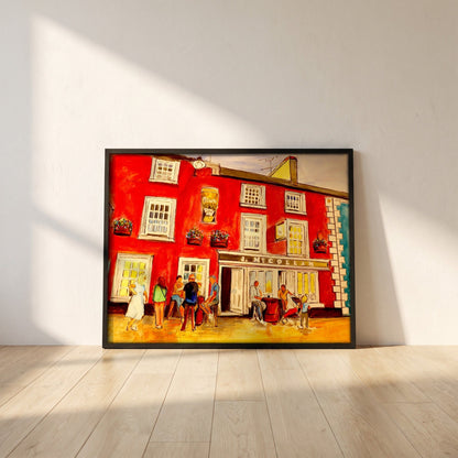 Johnny Joe's Pub, Cushendall framed print in a black frame leaning against a white plaster wall on oak floorboards in morning light