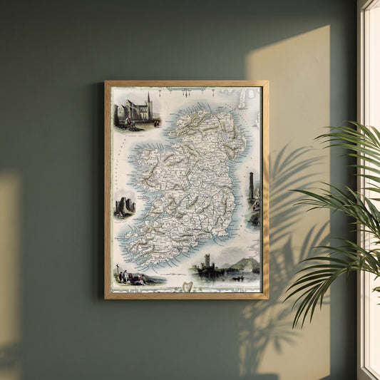 Old Map of Ireland framed print in a natural oak frame on a dark green wall beside a window, dappled plant shadow