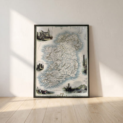 Old Map of Ireland framed print in a black frame leaning against a white plaster wall on oak floorboards in morning light
