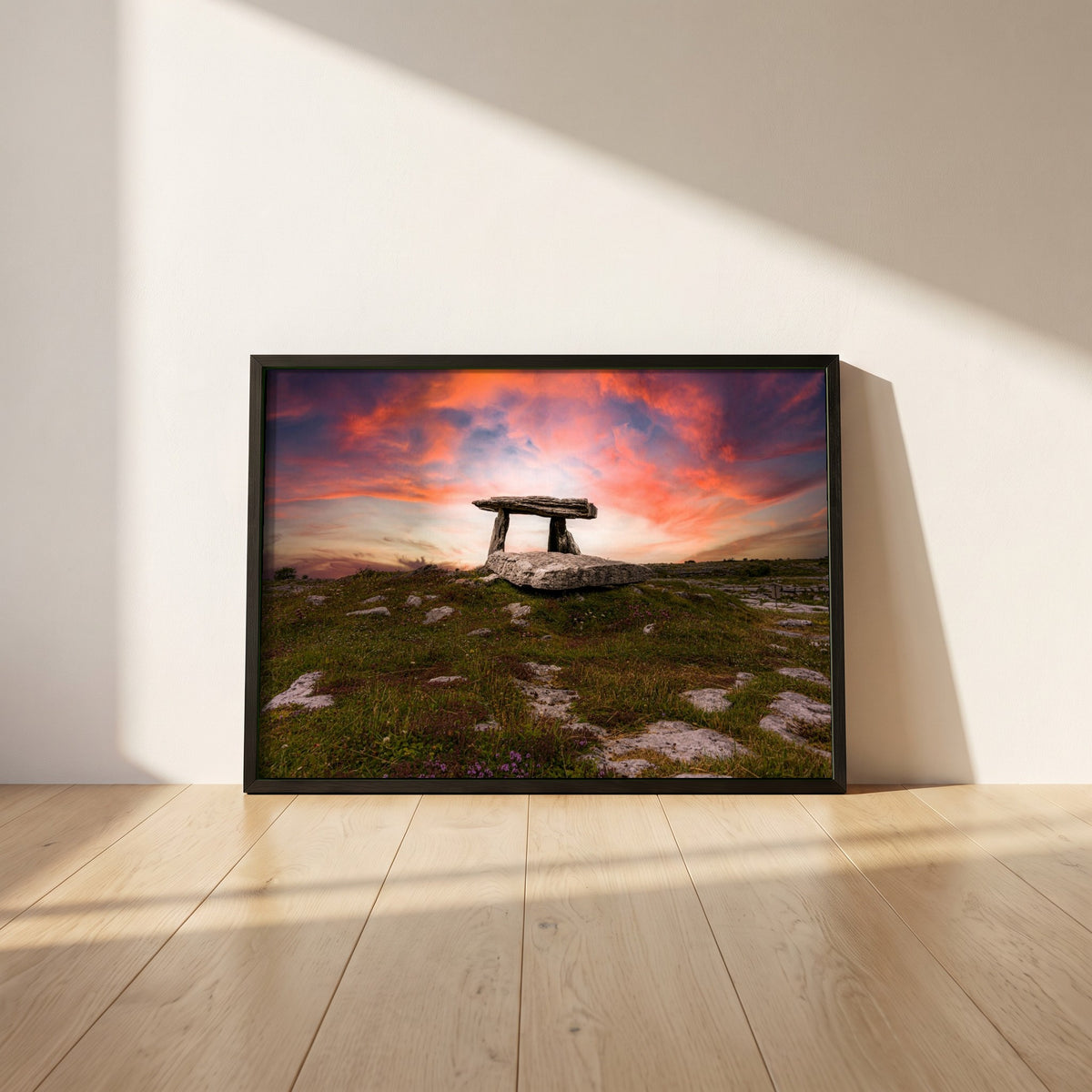 Poulnabrone Dolmen framed print in a black frame leaning against a white plaster wall on oak floorboards in morning light