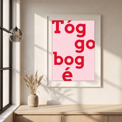 Tóg é go bog é framed print in a white frame on a plaster wall above an oak worktop in a bright Scandinavian kitchen
