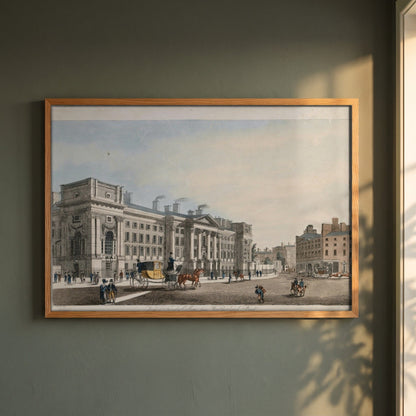 Trinity College Dublin from Westmoreland Street framed print in a natural oak frame on a dark green wall beside a window, dappled plant shadow